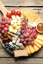 Photo of Different types of delicious cheese and other snacks on wooden table, top view