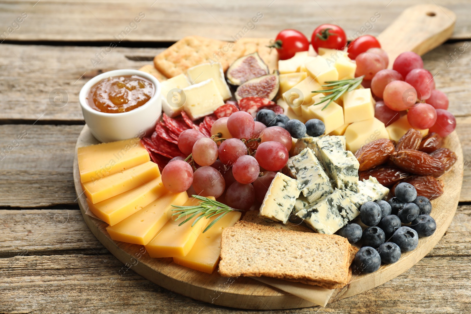 Photo of Different types of delicious cheese and other snacks on wooden table, closeup