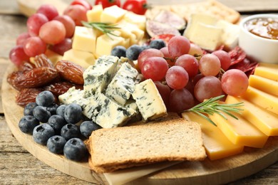 Photo of Different types of delicious cheese and other snacks on wooden table, closeup