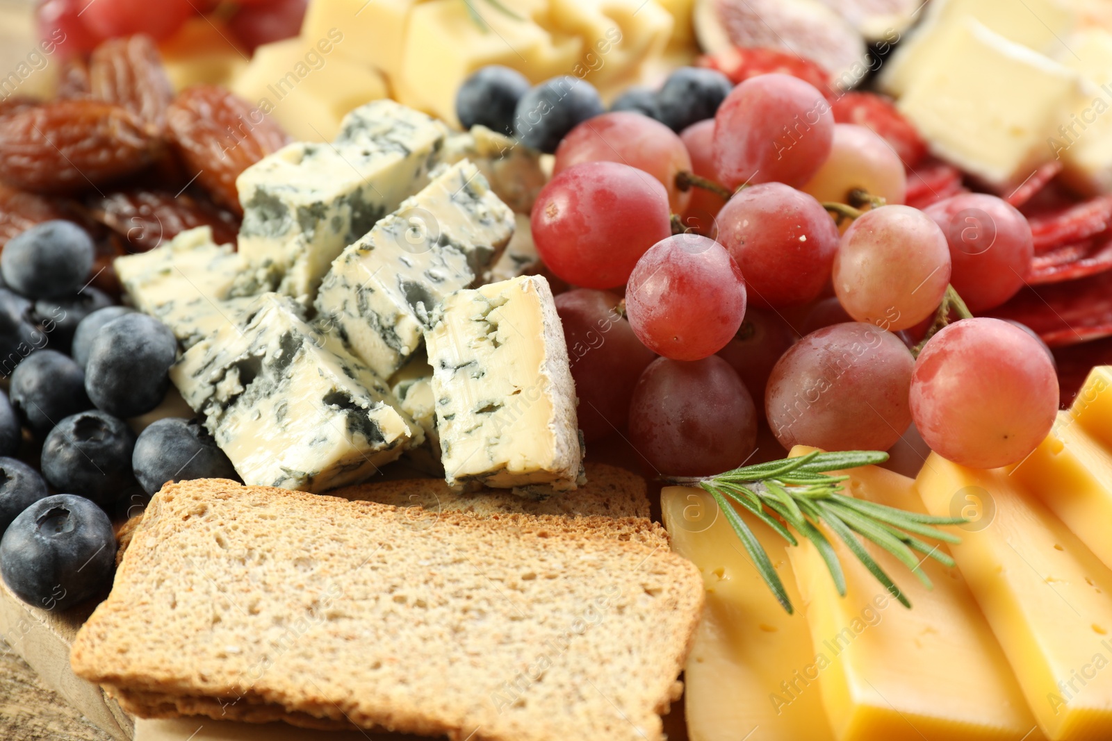 Photo of Different types of delicious cheese and other snacks as background, closeup