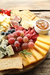 Photo of Different types of delicious cheese and other snacks on wooden table, closeup