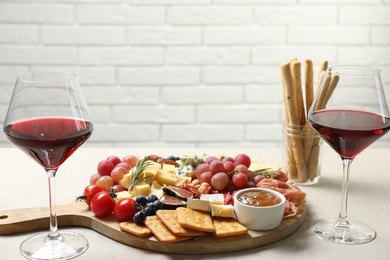 Photo of Different types of delicious cheese, other snacks and wine on light grey table