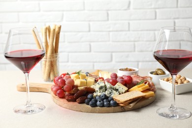 Photo of Different types of delicious cheese, other snacks and wine on light grey table