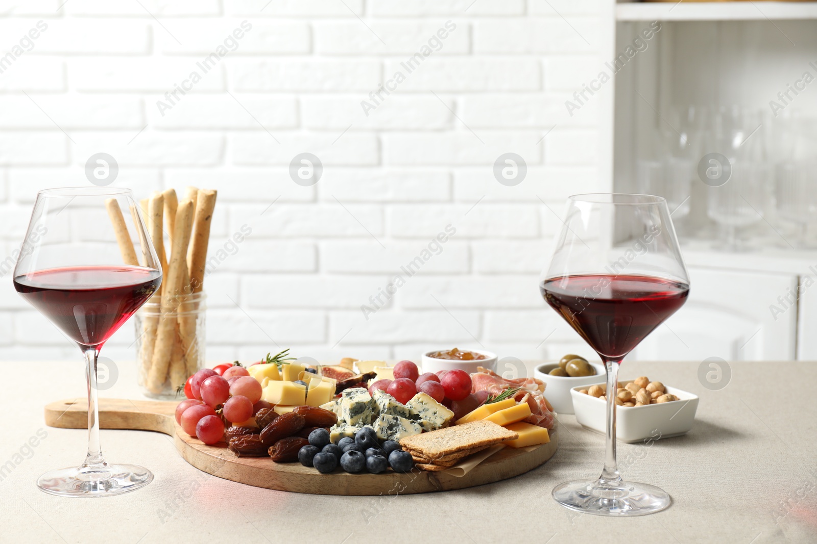 Photo of Different types of delicious cheese, other snacks and wine on light grey table