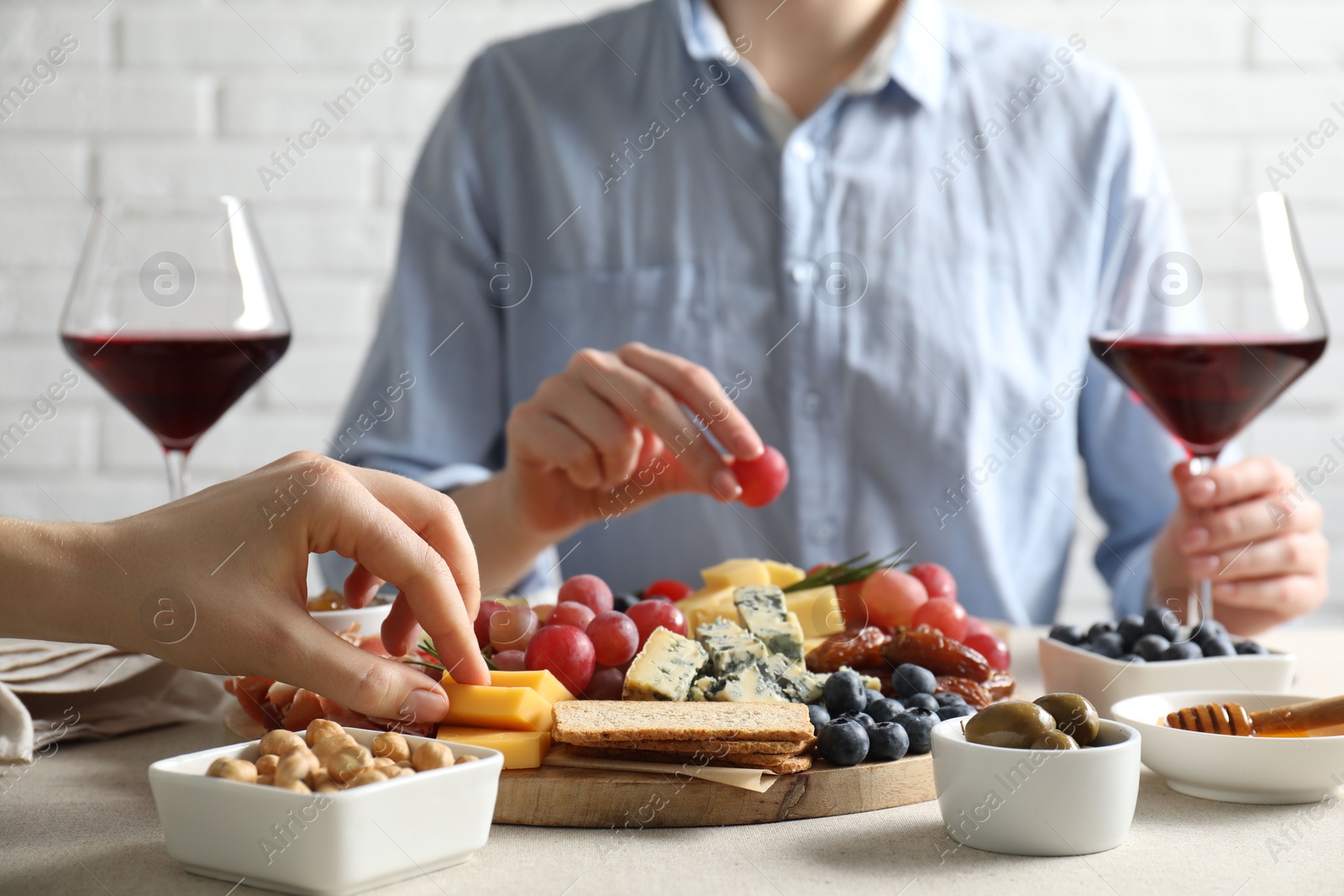 Photo of Women enjoying different snacks and wine during brunch at light grey table indoors, closeup