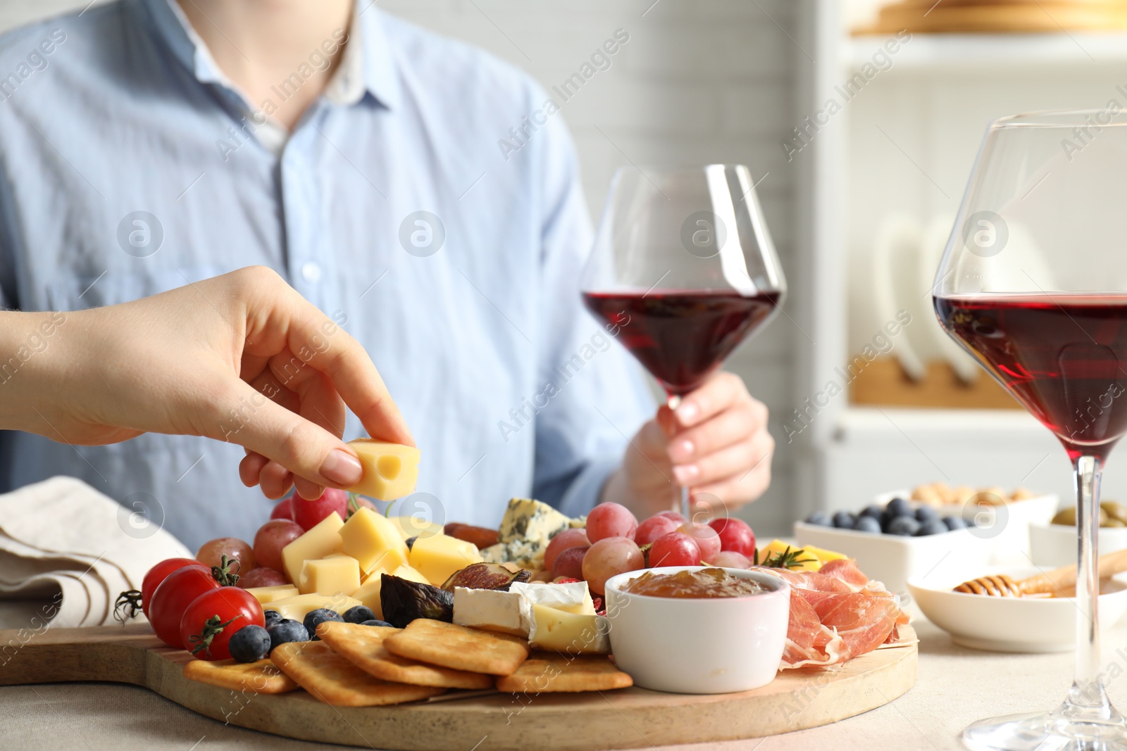 Photo of Women enjoying different snacks and wine during brunch at light grey table indoors, closeup