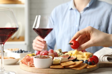 Photo of Women enjoying different snacks and wine during brunch at light grey table indoors, closeup