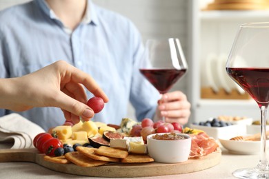 Photo of Women enjoying different snacks and wine during brunch at light grey table indoors, closeup