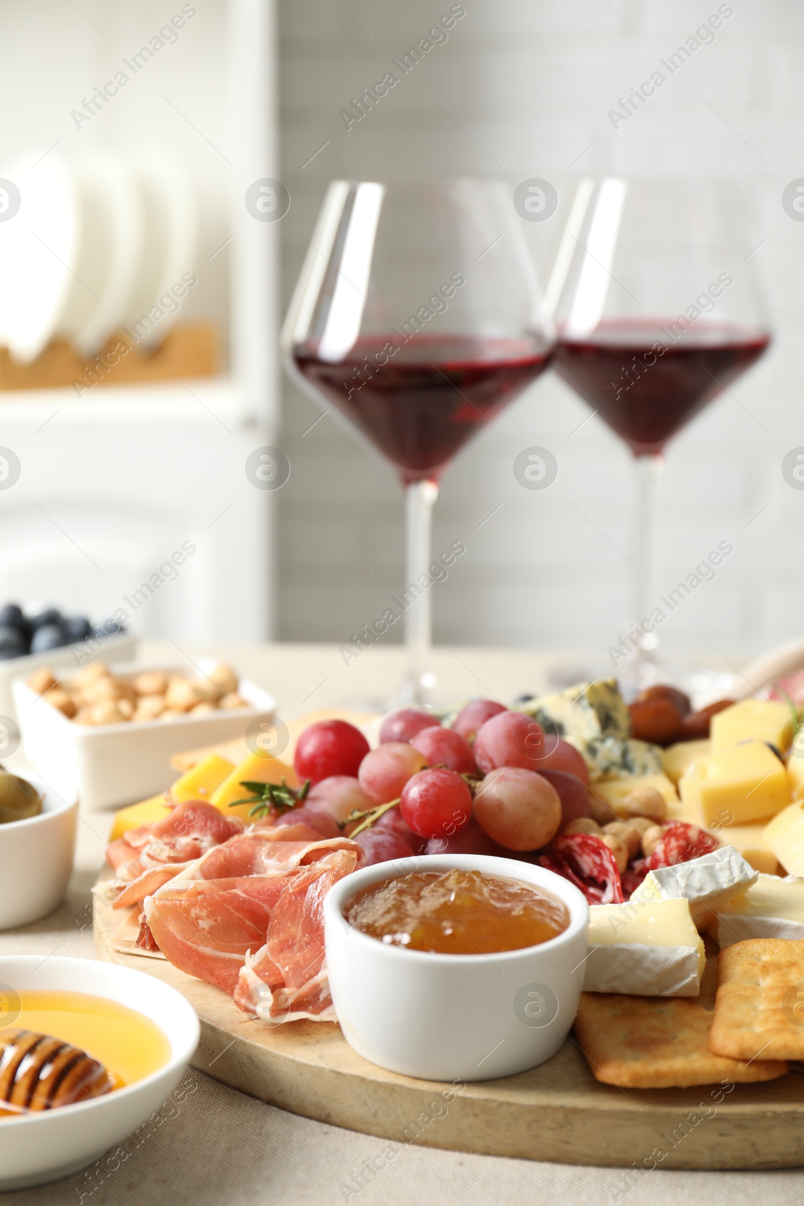 Photo of Different types of delicious cheese, other snacks and wine on light grey table, closeup