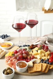 Photo of Different types of delicious cheese, other snacks and wine on light grey table