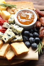 Photo of Different types of delicious cheese and other snacks on wooden table, closeup