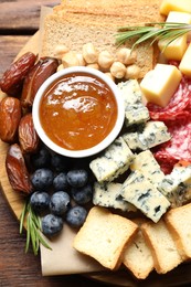 Photo of Different types of delicious cheese and other snacks on wooden table, top view