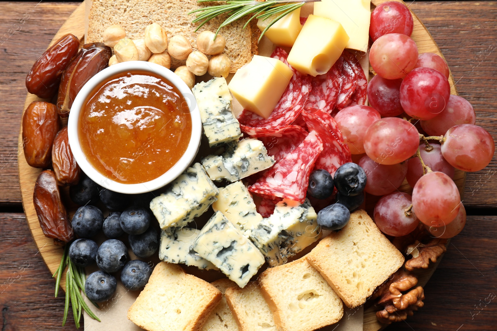 Photo of Different types of delicious cheese and other snacks on wooden table, top view