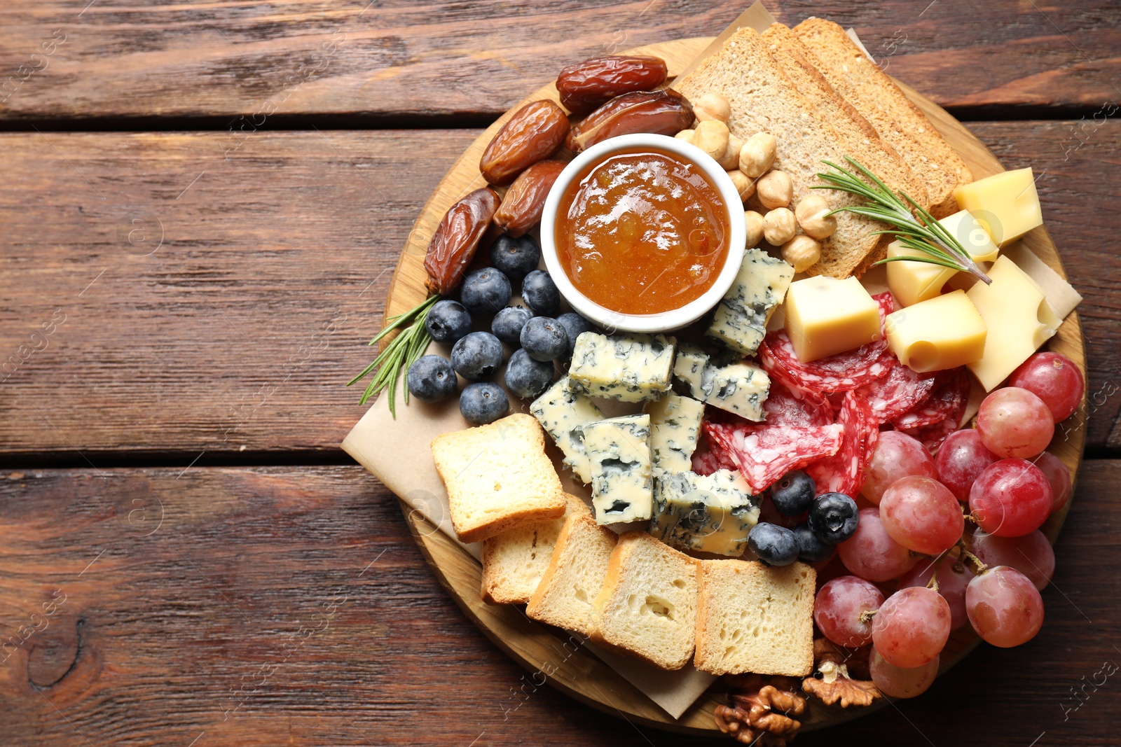 Photo of Different types of delicious cheese and other snacks on wooden table, top view. Space for text