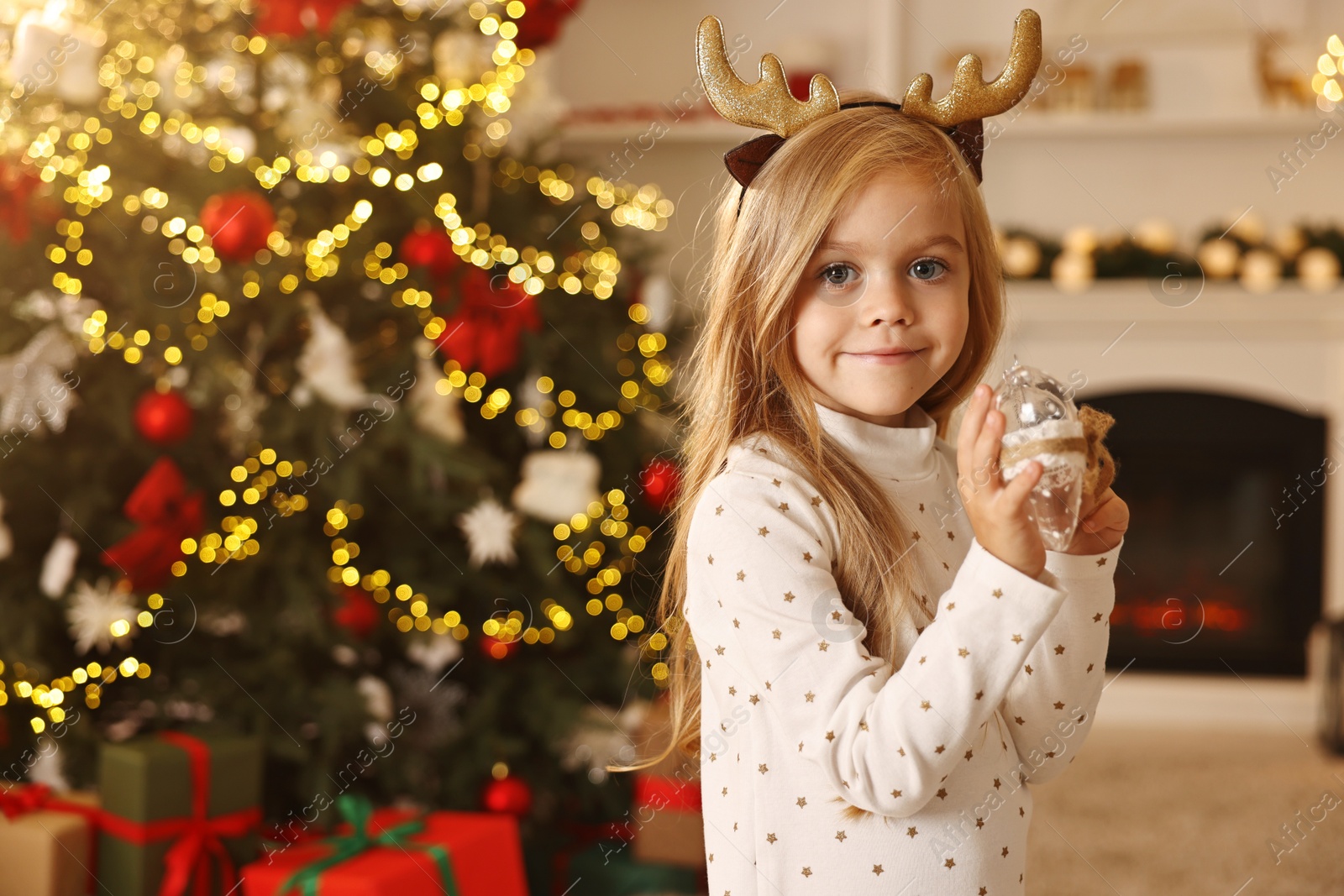 Photo of Little girl with Christmas ornament at home, space for text