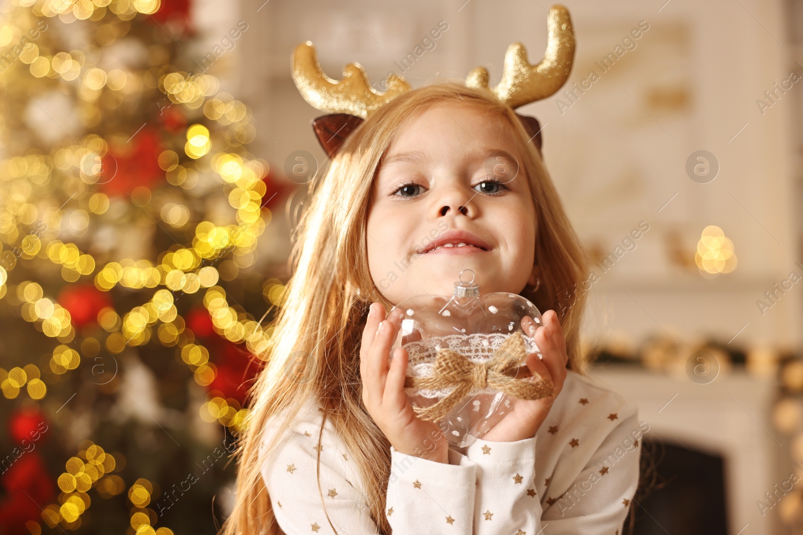 Photo of Little girl with Christmas ornament at home