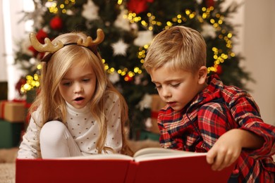 Photo of Little kids reading book at home. Christmas celebration