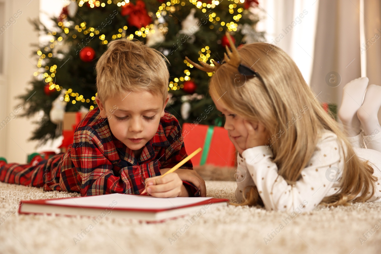 Photo of Little kids writing letter to Santa Claus on floor at home. Christmas celebration