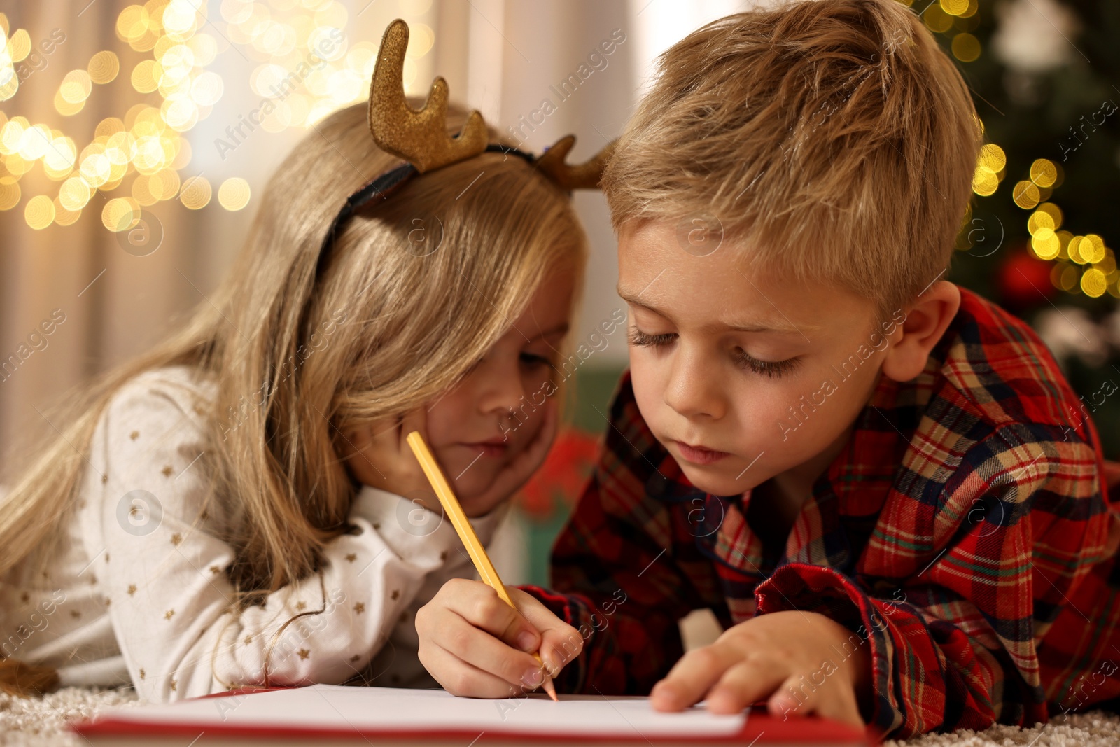 Photo of Little kids writing letter to Santa Claus on floor at home. Christmas celebration