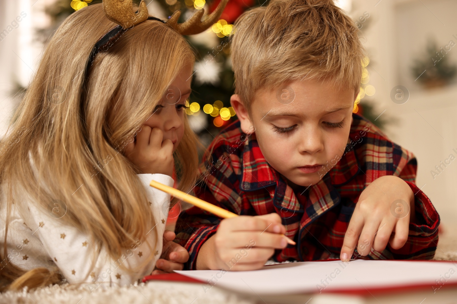 Photo of Little kids writing letter to Santa Claus on floor at home. Christmas celebration