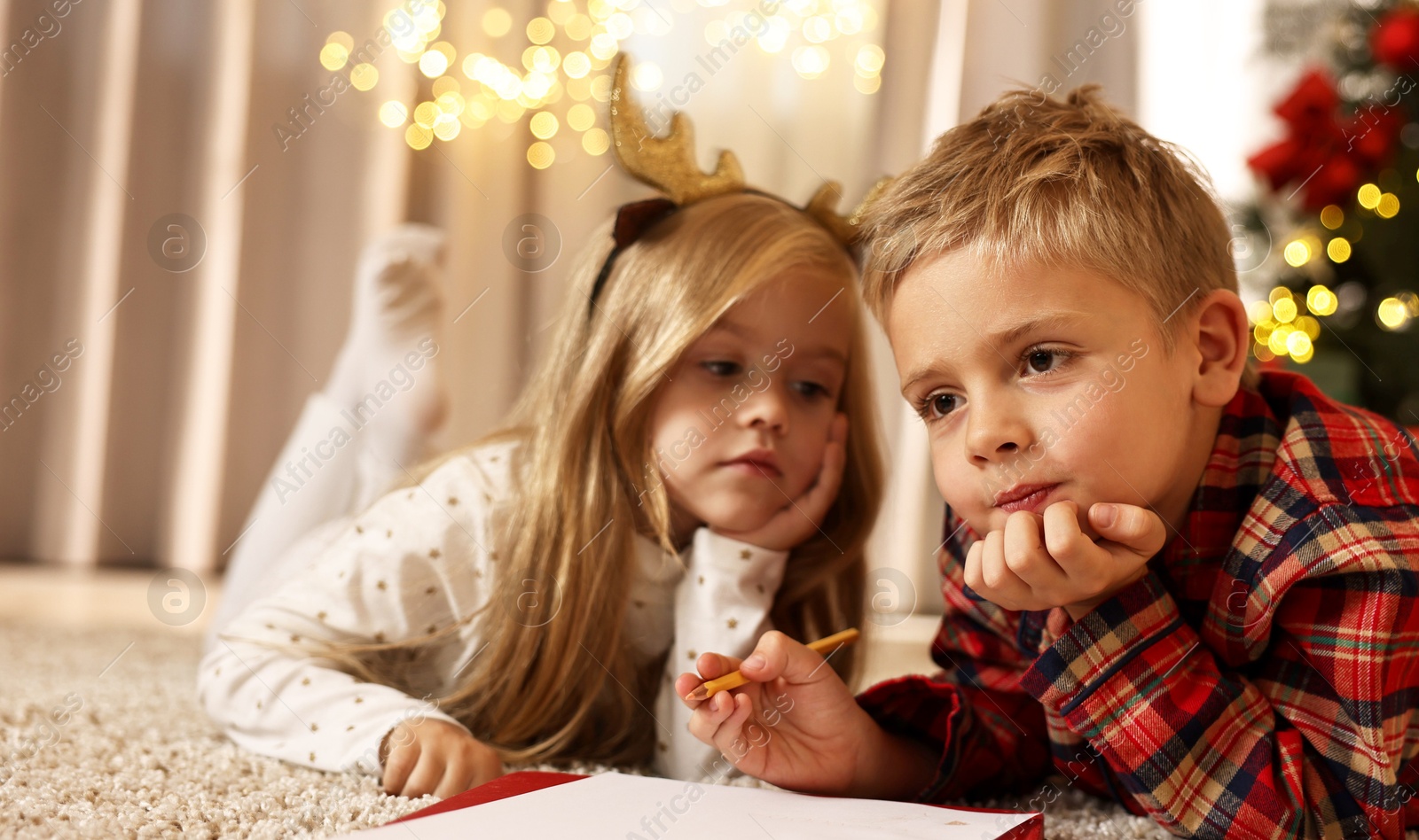 Photo of Little kids writing letter to Santa Claus on floor at home. Christmas celebration