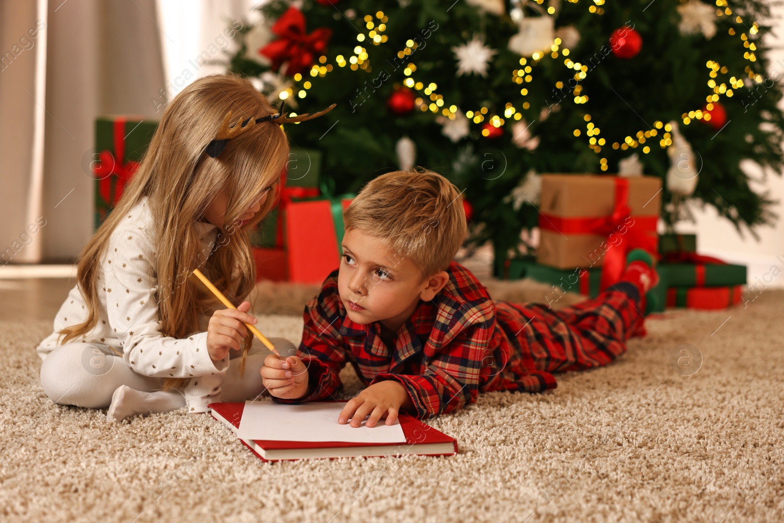 Photo of Little kids writing letter to Santa Claus on floor at home. Christmas celebration