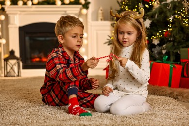 Photo of Little kids with candy canes on floor at home. Christmas celebration