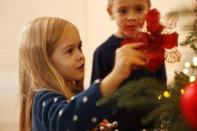 Photo of Little kids decorating Christmas tree at home