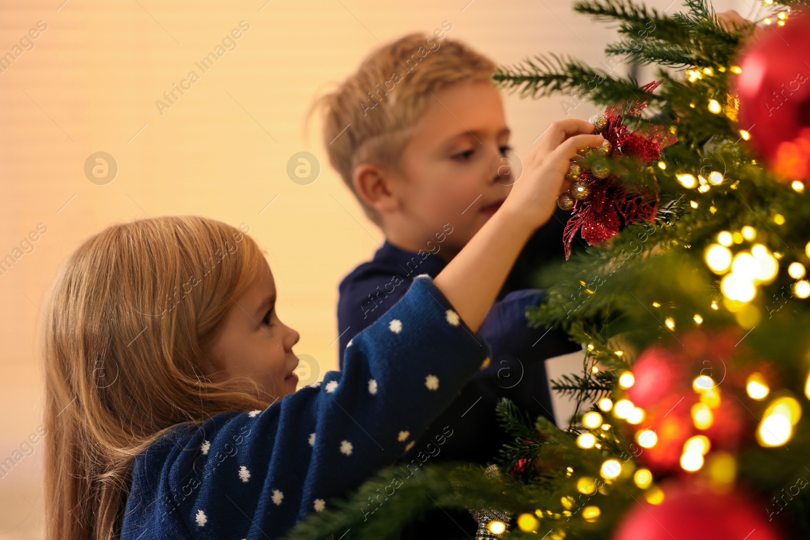 Photo of Little kids decorating Christmas tree at home