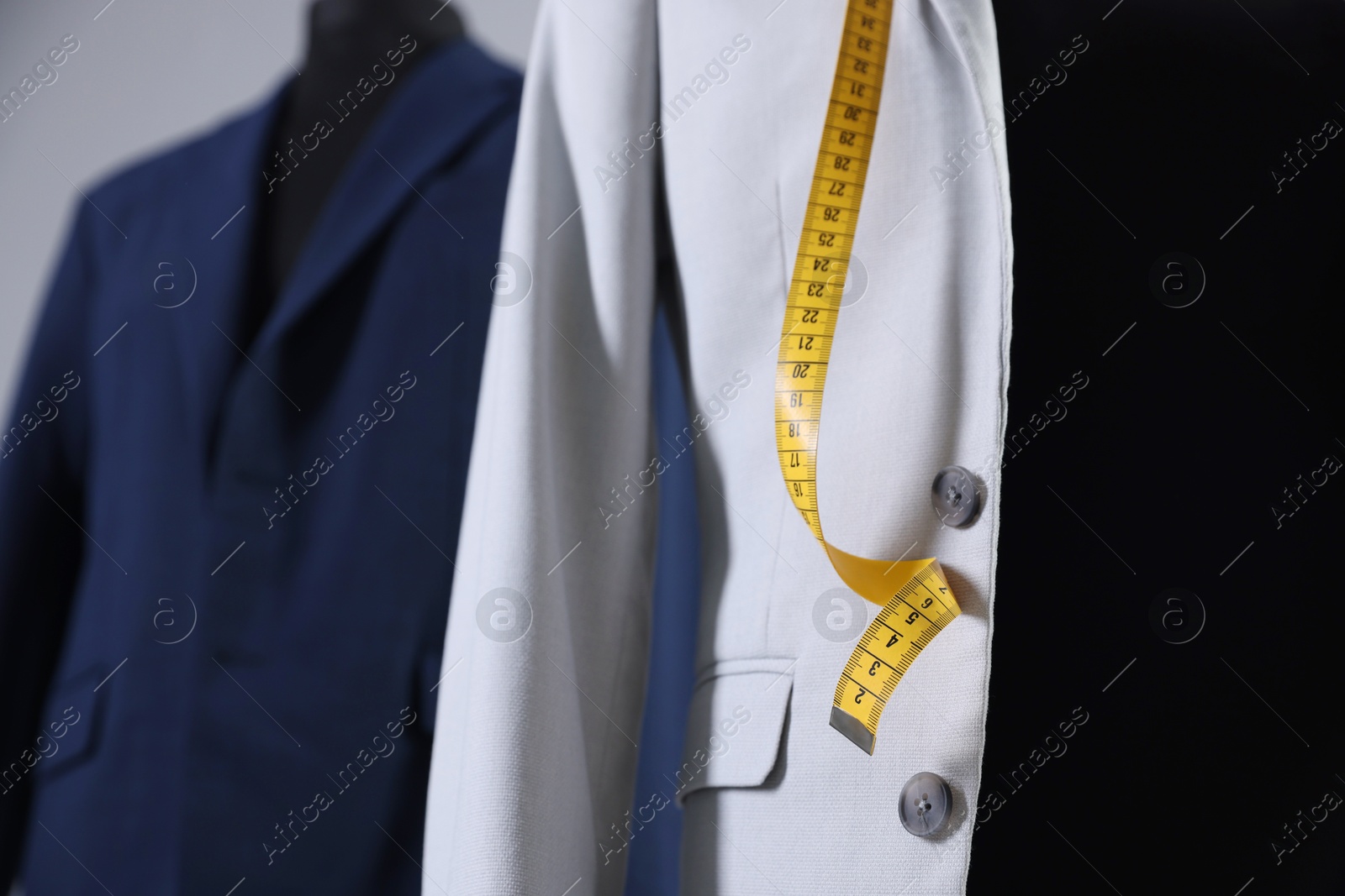 Photo of Female mannequin with jacket and measuring tape in tailor shop, closeup