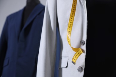 Photo of Female mannequin with jacket and measuring tape in tailor shop, closeup