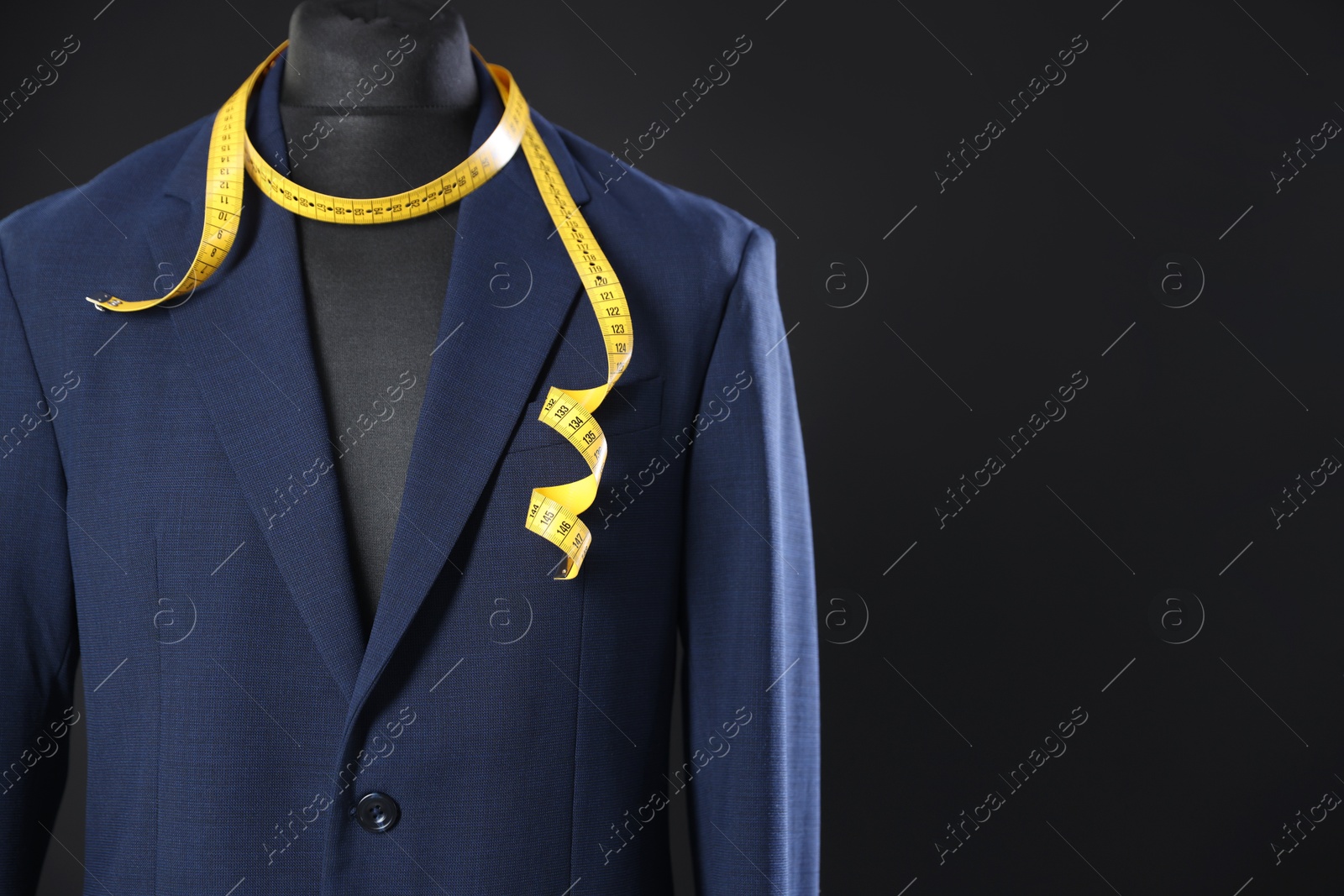 Photo of Male mannequin with jacket and measuring tape on dark background, closeup. Space for text