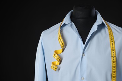 Photo of Male mannequin with shirt and measuring tape on black background, closeup