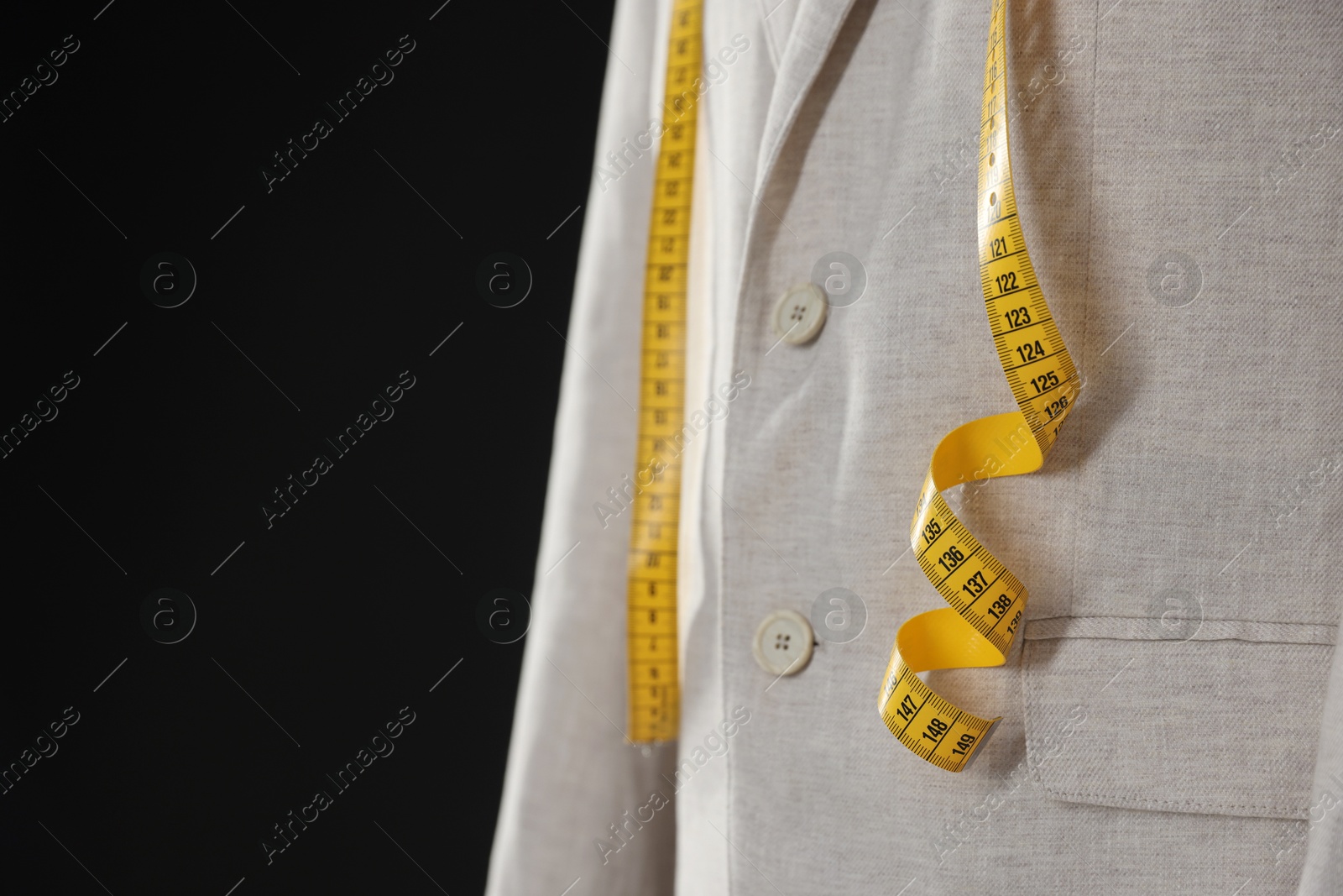 Photo of Male mannequin with jacket and measuring tape on black background, closeup. Space for text