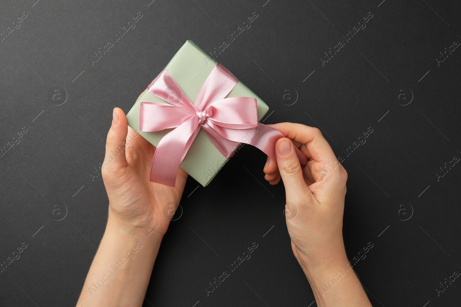 Photo of Woman opening gift box on black background, top view