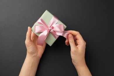 Photo of Woman opening gift box on black background, top view