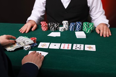 Photo of Gambler making bet with professional croupier at gambling table, closeup