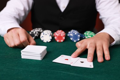 Photo of Professional croupier with playing cards at gambling table, closeup