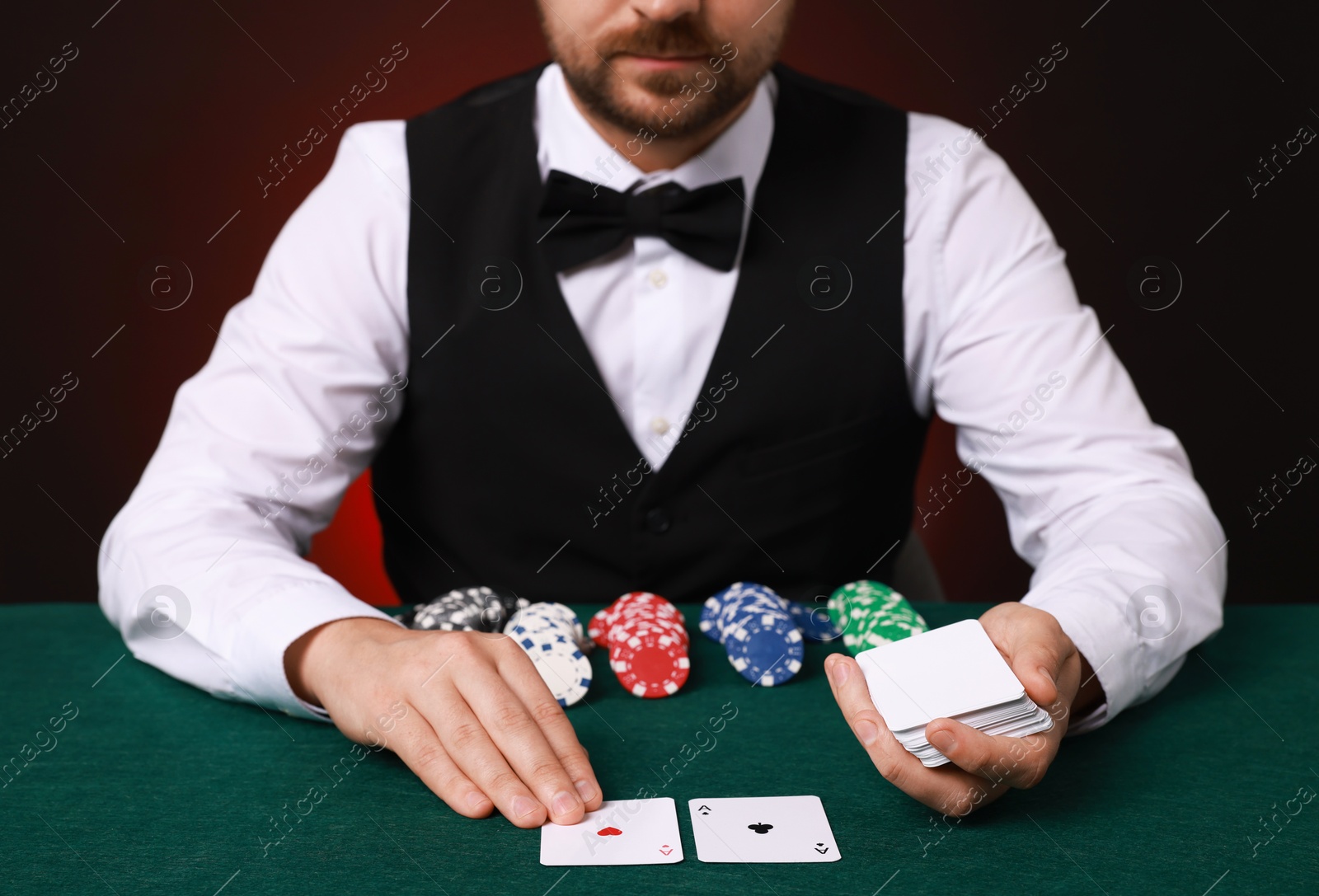 Photo of Professional croupier with playing cards at gambling table, closeup