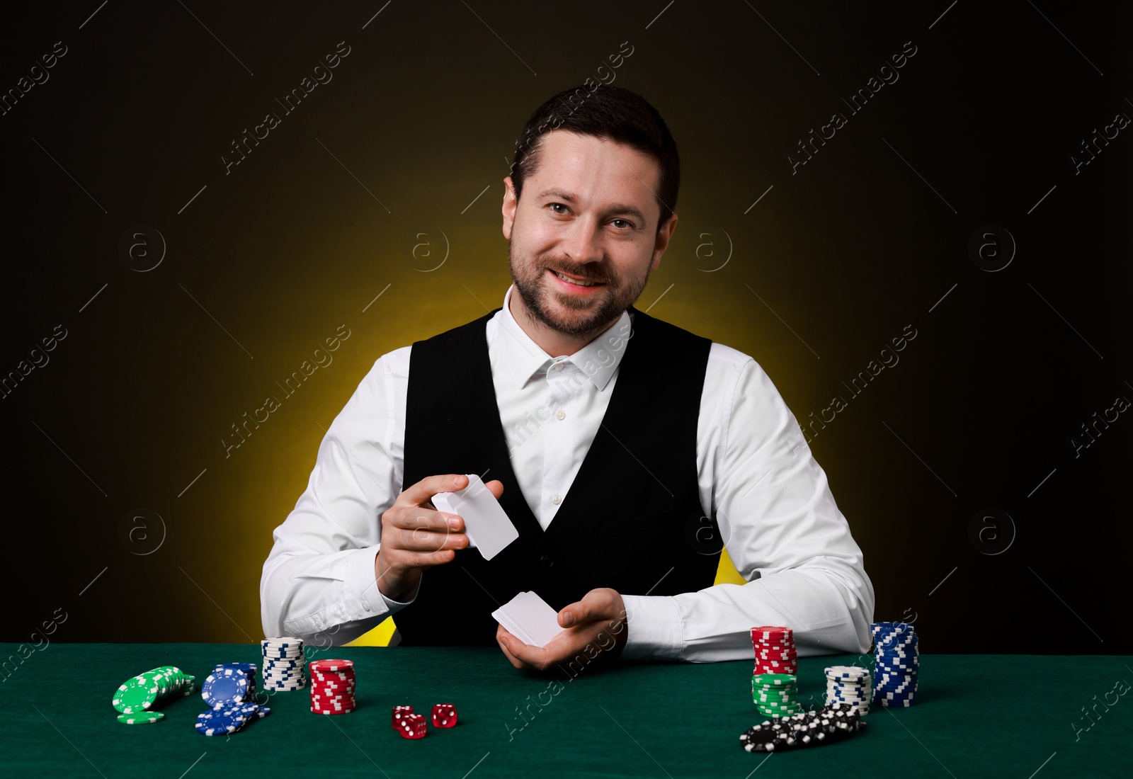 Photo of Professional croupier shuffling cards at gambling table on dark yellow background