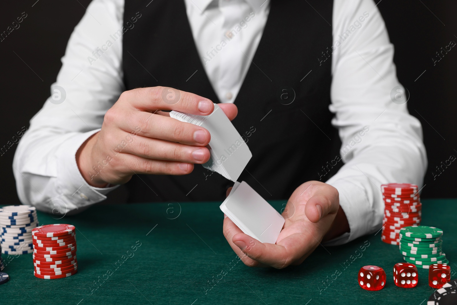 Photo of Professional croupier shuffling cards at gambling table, closeup