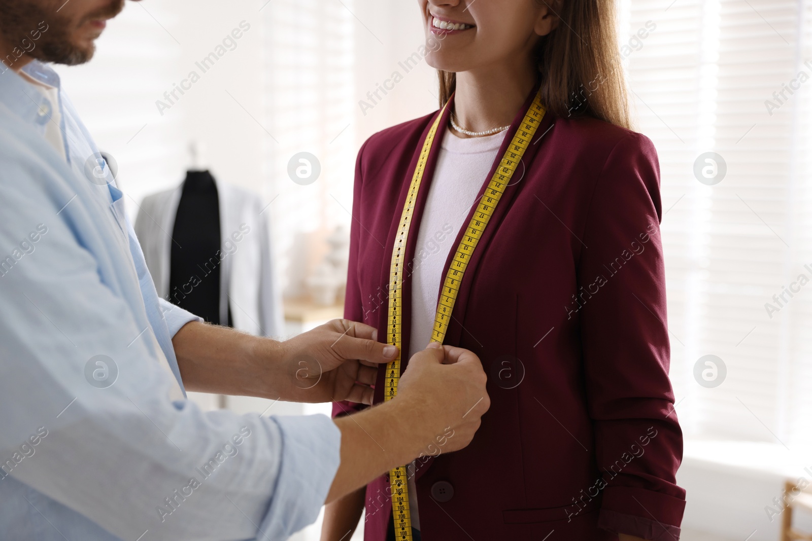 Photo of Man measuring woman's jacket with tape in atelier, closeup