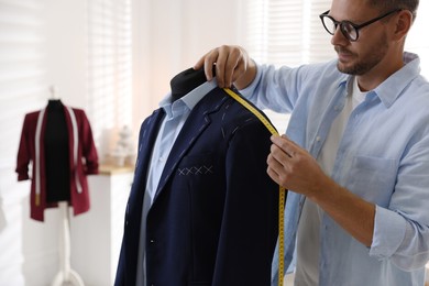 Photo of Man measuring black jacket with tape in atelier