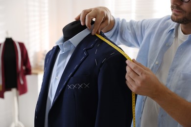 Photo of Man measuring black jacket with tape in atelier, closeup