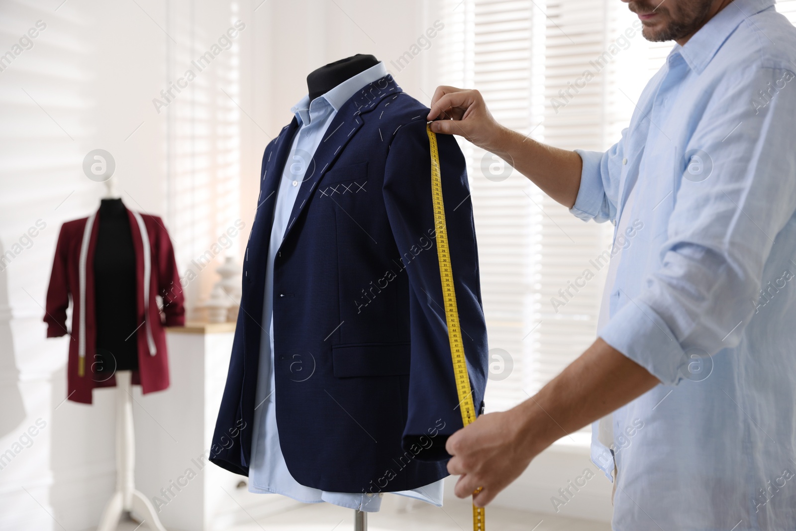 Photo of Man measuring black jacket with tape in atelier, closeup