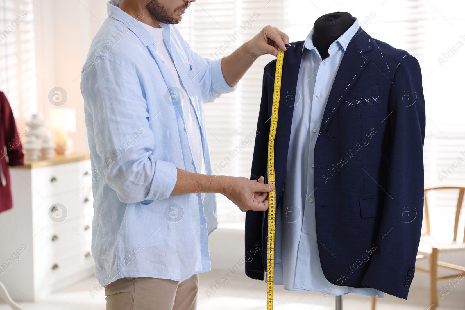 Photo of Man measuring black jacket with tape in atelier, closeup