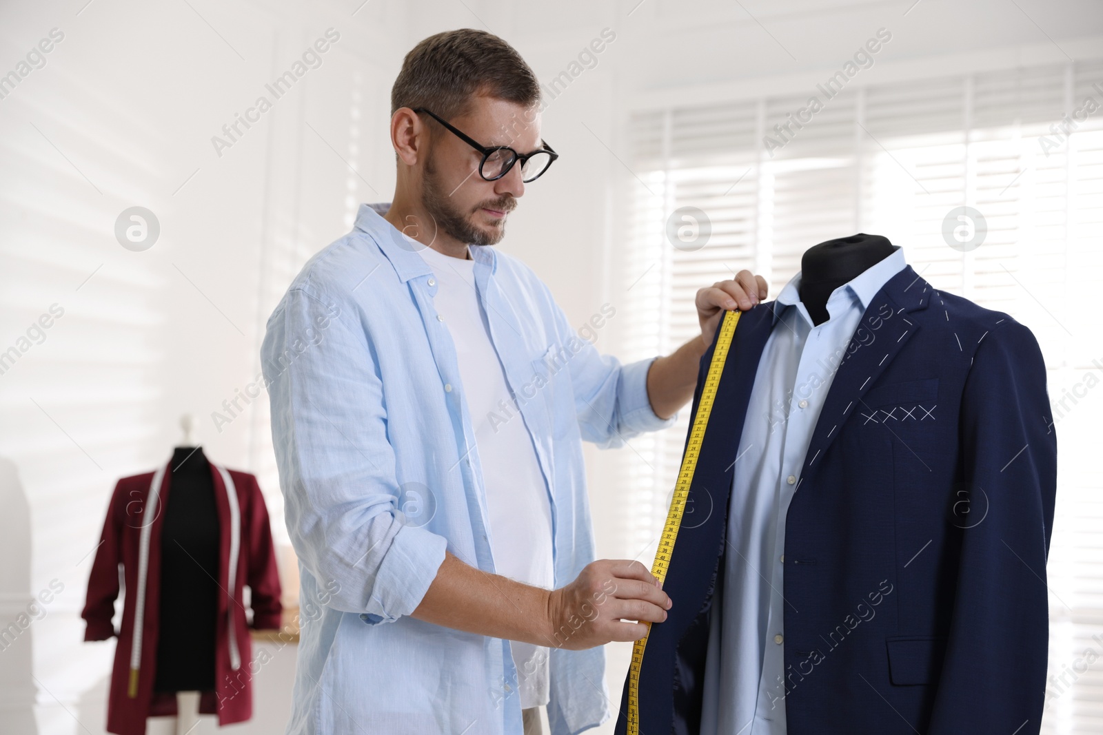 Photo of Man measuring black jacket with tape in atelier