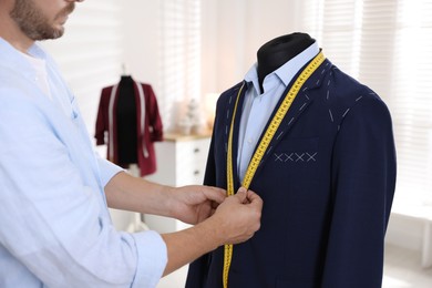 Photo of Man measuring black jacket with tape in atelier, closeup