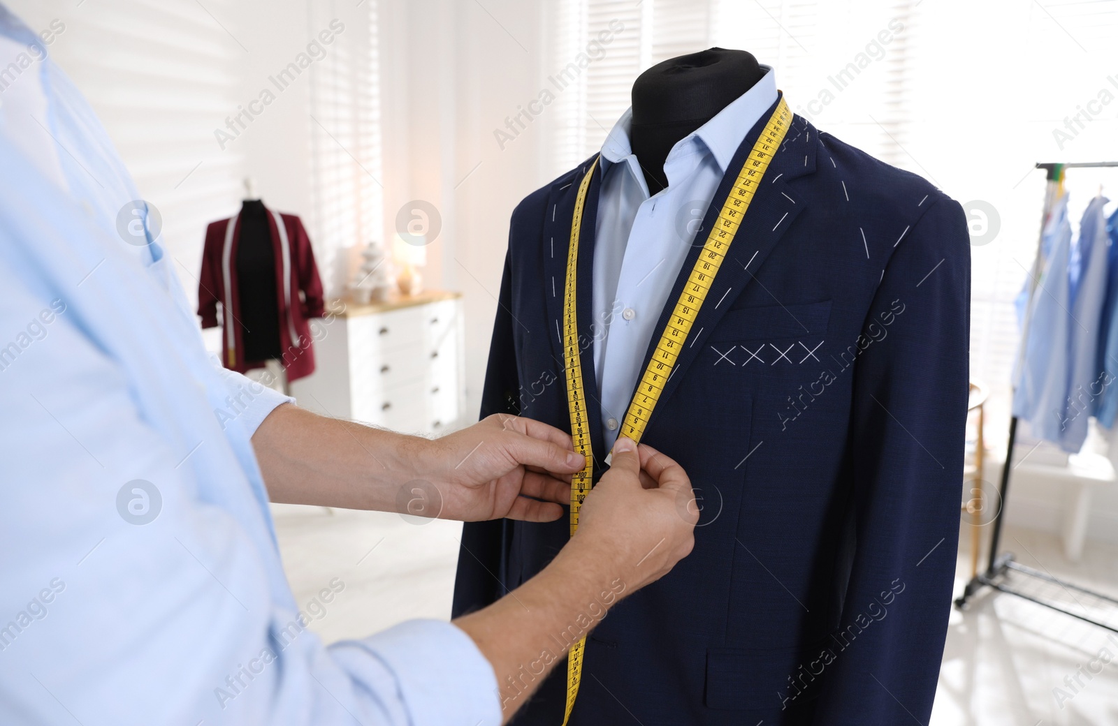 Photo of Man measuring black jacket with tape in atelier, closeup