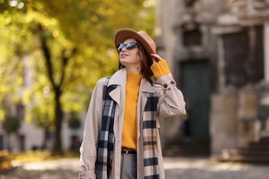 Photo of Charming young woman in stylish outfit on city street. Autumn season